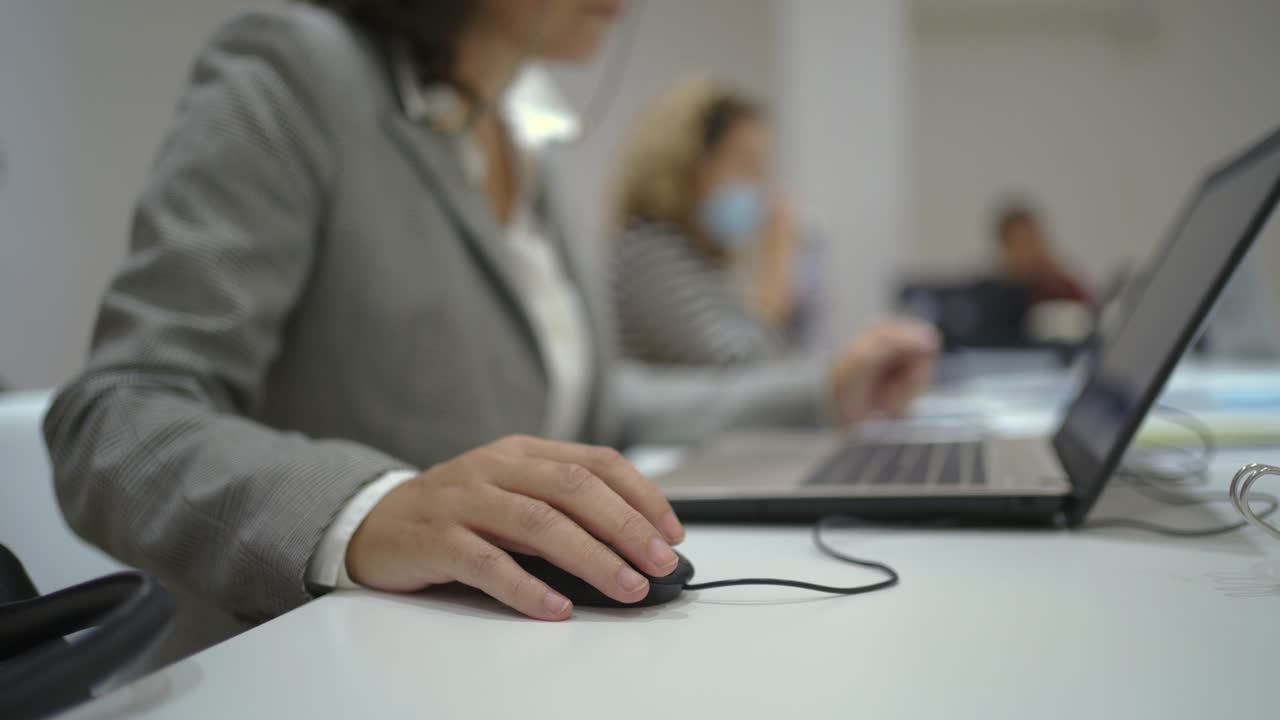 mujer anónima trabajando en una computadora portátil en la oficina