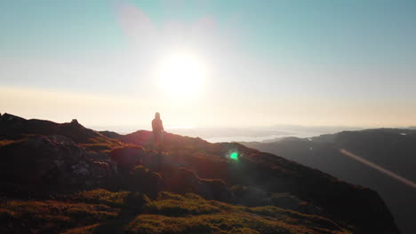 Man-walking-at-the-end-of-a-cliff,-photographing-the-beautiful-landscape---Aerial-4K