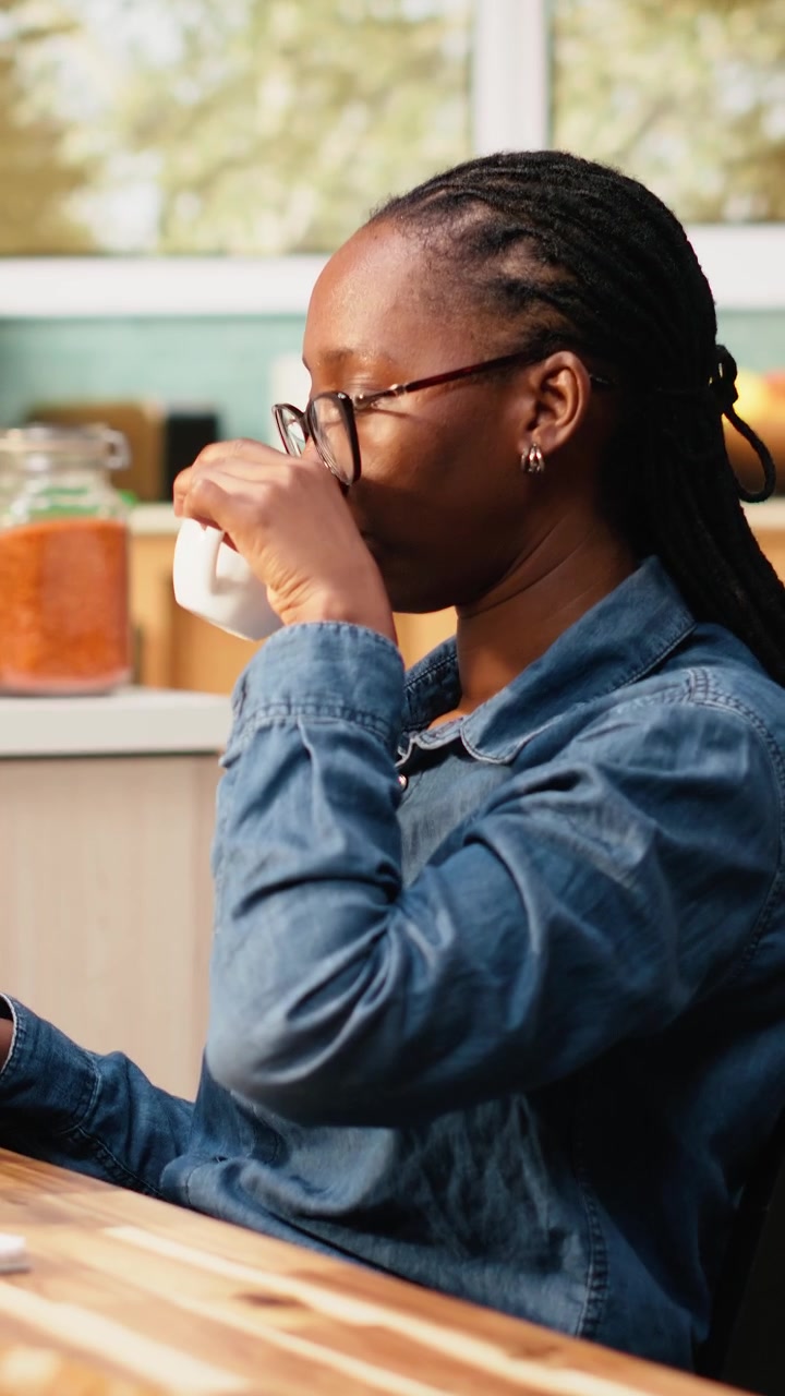 Vertical Video Black woman programming on laptop in kitchen representing hybrid work