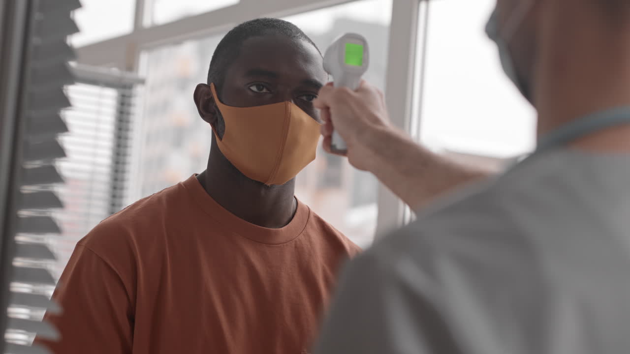 간호사 는 아프리카 사람 의 온도 를 측정 하고 있다