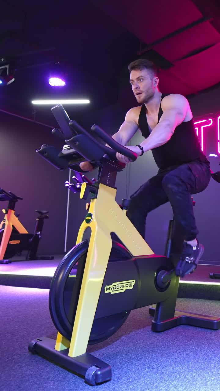 Man exercising in fitness club. Muscular athletic bodybuilder fitness man sitting stationary bicycle in gym