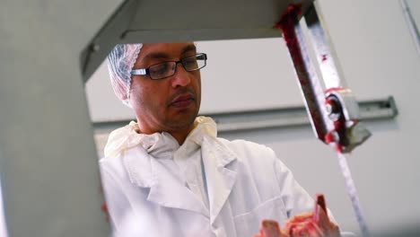 butcher cutting raw meat on a band saw machine