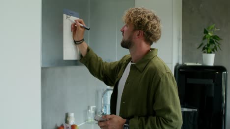 man planning his schedule in the kitchen