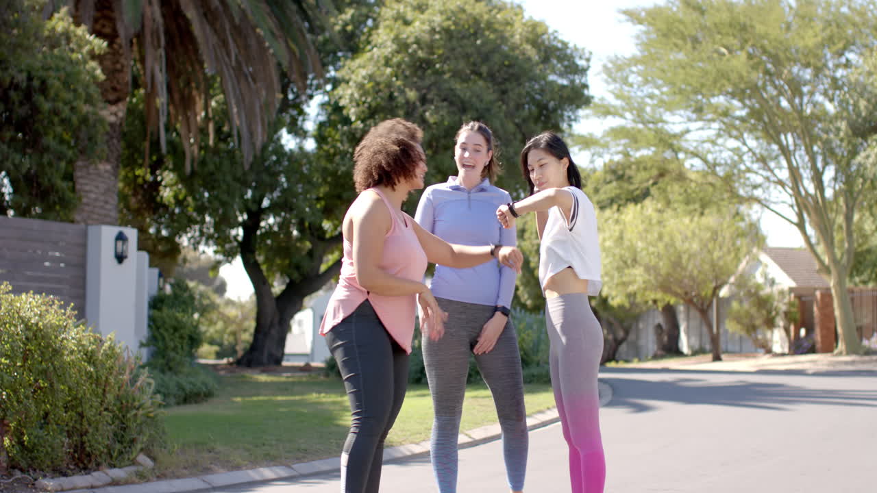 Exercising outdoors, three women friends in activewear chatting and laughing together