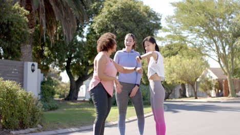 exercising outdoors, three women friends in activewear chatting and laughing together
