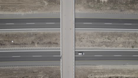 vertical top down timelapse of a farm bridge over highway crossroads in summer, aerial drone view - raw file d-log