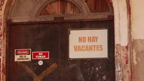 no contratar un cartel pegado a una antigua gran puerta de entrada a un edificio histórico en el que se están realizando trabajos de restauración y construcción, mostrando la falta de oportunidades laborales creada por la pandemia