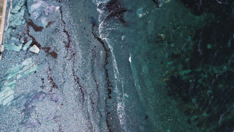 Calm-New-England-ocean-waves-crash-on-grey-pebble-beach-at-Brenton-Point-State-Park