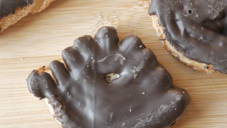 a hand-shaped chocolate-covered palmera pastry, close-up shot on a wooden surface
