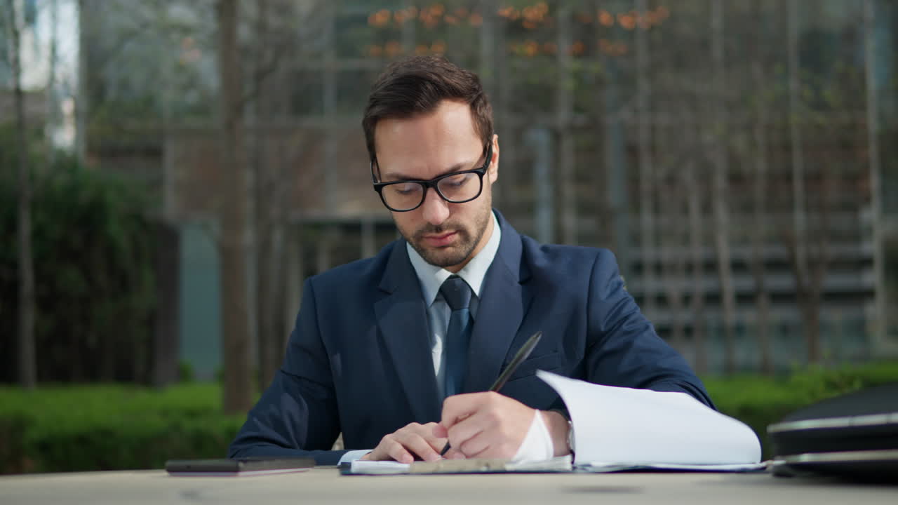 Confused stuck thoughtfull businessman holding pan in hand but don't know what to write, Man review documents in a city park by the office in a fresh air