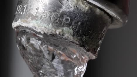 running water from dirty tap with hard water deposits