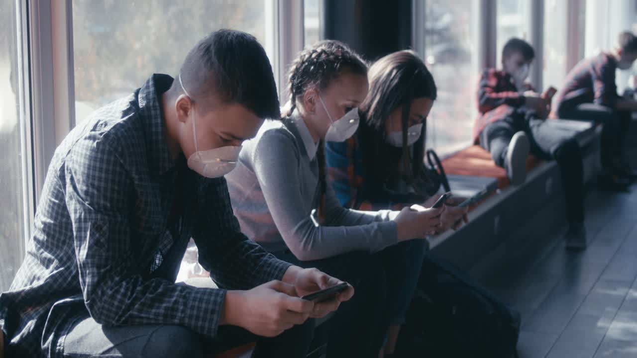Teenagers Waiting Indoors Wearing Masks