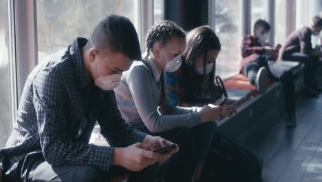 teenagers waiting indoors wearing masks