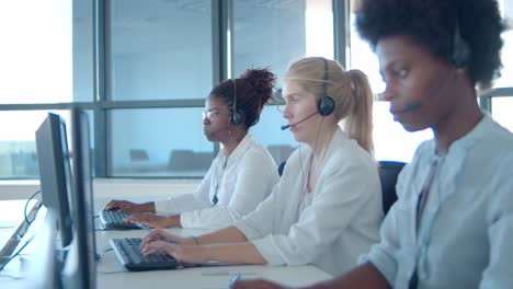 focused diverse operators in headsets working at computers