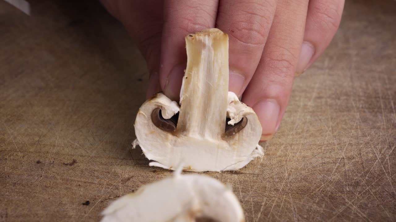 Primo piano di un fungo champignon affettato su un tagliere di legno a marzo.