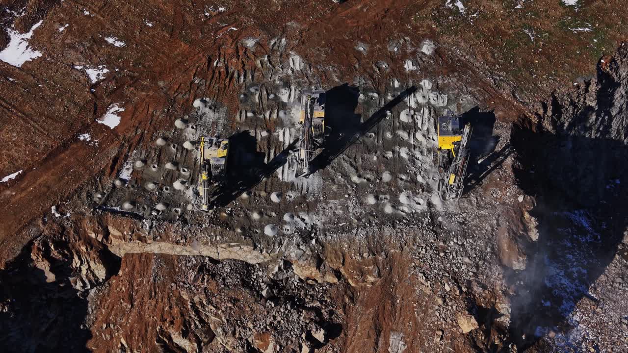 Due grandi macchine operano su un terreno roccioso in un sito minerario.