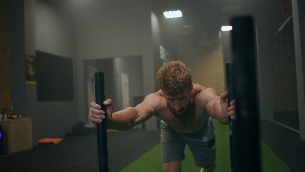 단호 한 마음 을 가진 남자 운동 선수 는 체육관 에서 무거운  ⁇ 매 를 밀고 있다.