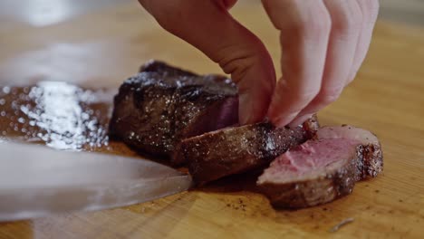 cutting fried steak into pieces on a wooden cut board with a steel knife