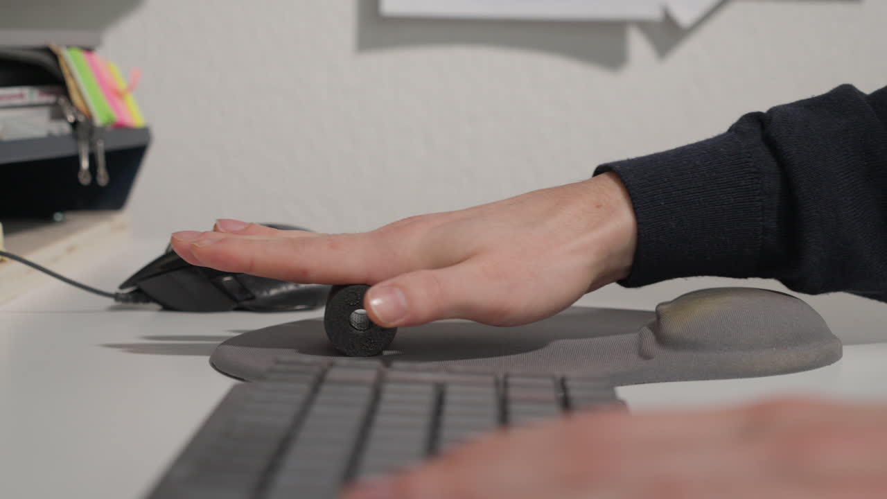 Man massaging his hand with a foam roller after mouse overuse