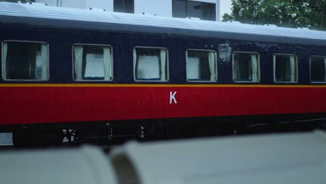 heavy rain at a train station in phnom penh, with a close-up of a red and blue train car