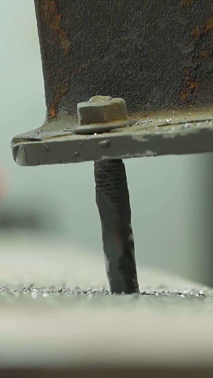 Metal detail connected to beam with old screws and operating tool on background in plant workshop closeup. Restoration of rusty steel construction