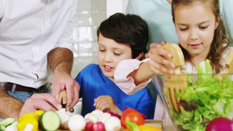 padres ayudando a los niños a preparar ensalada