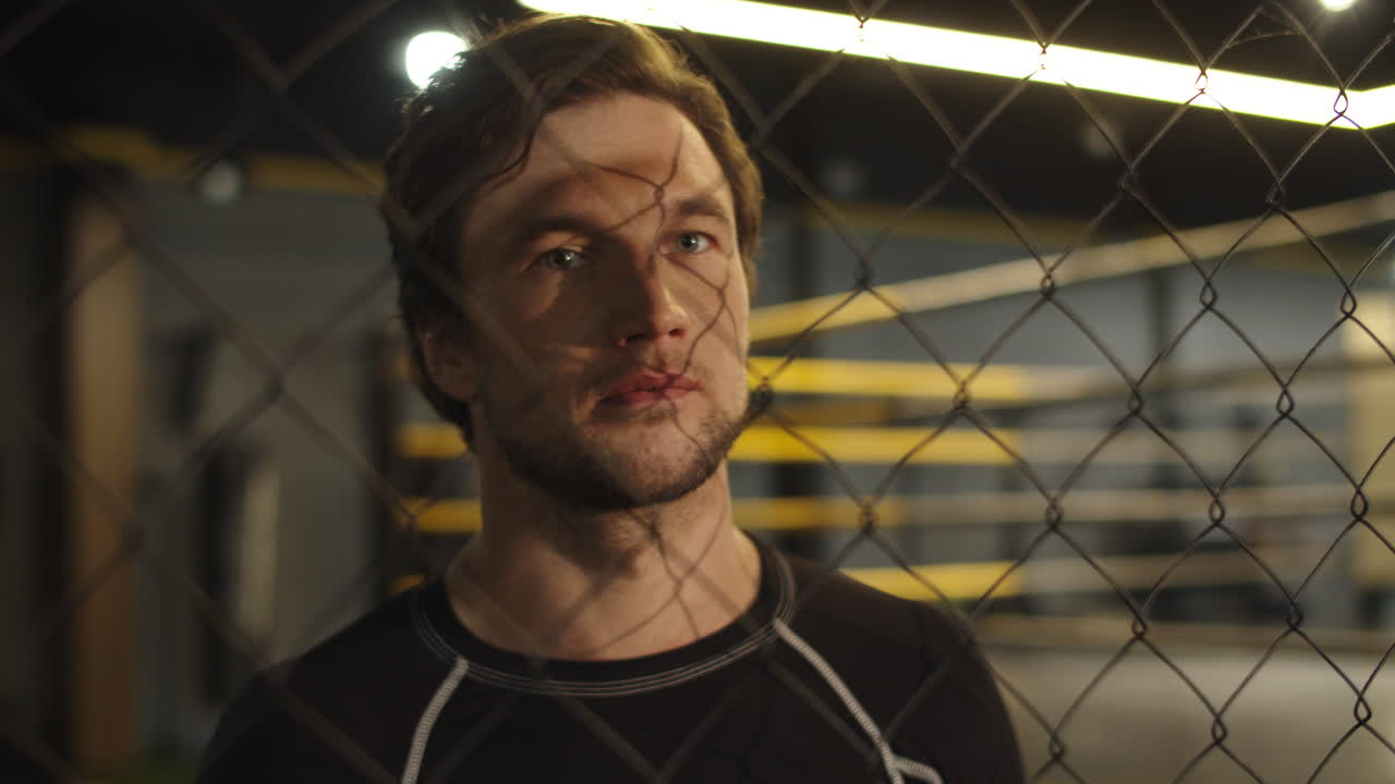 스포츠 클럽에서 링 근처를  ⁇ 고 있는 예쁜  ⁇ 한 남자. 체육관에서 카메라를 보는 권투 선수