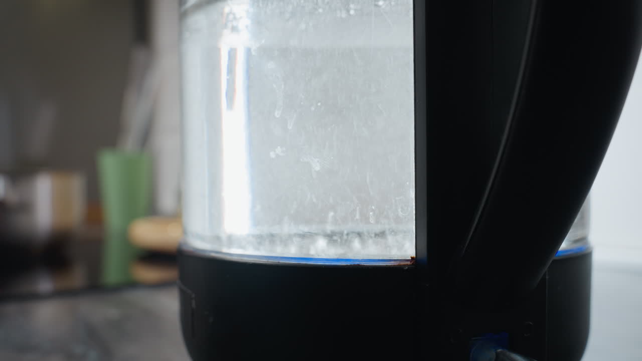 투명한 항아리에 있는 는 물의 클로즈업으로 눈에 보이는 거품이 상승하며, 전기 물 비에서 물을 가열하는 과정을 보여줍니다. 는 액체에 초점을 맞추기 위해 배경이 흐릿합니다.