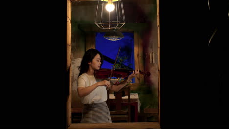 hermosa mujer profundamente perdida en tocar el violín melódico en casa