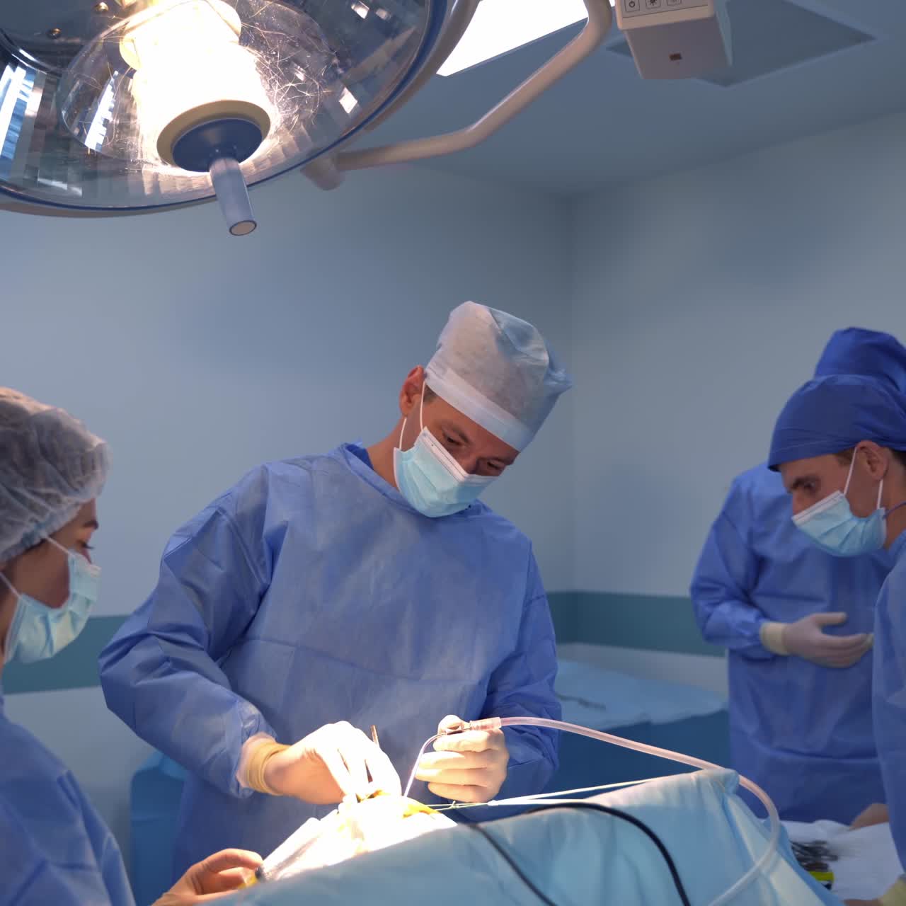 Chief surgeon assisted by a team operates the patient. Doctor uses tools in surgery and changes them helped by the assistant