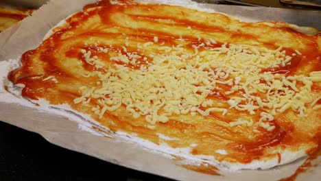la cocinera casera está vertiendo queso recién rallado en pizza casera