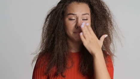 caucasian curly haired woman sneezing in front of the camera.