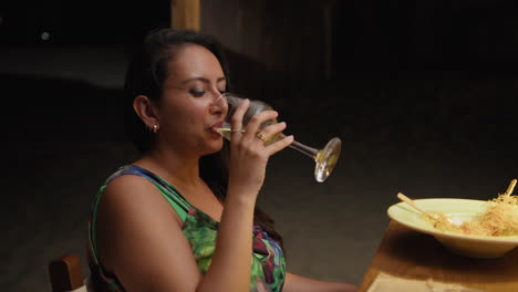 woman smiling and drinking wine feeling happy during the restaurant dinner