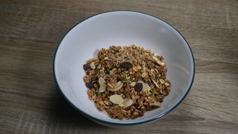 granola en un tazón y luego se coloca una cuchara dentro del tazón excavando en la granola hecha de semillas, frutos secos, nueces, pasas, desayuno saludable