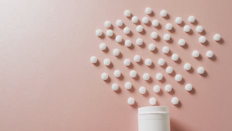 video of white pill box and white pills arranged on pink background with copy space