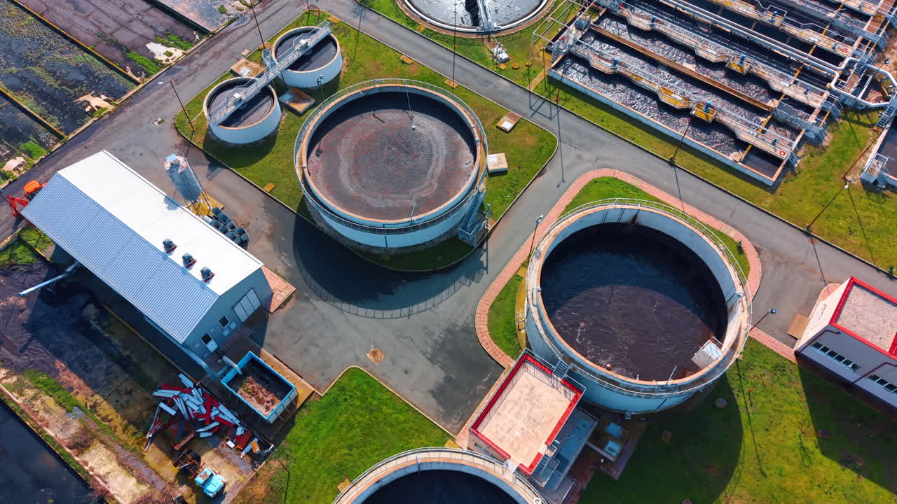 Water treatment facility seen from above. The view shows a water treatment facility with large circular tanks and buildings next to them during daytime