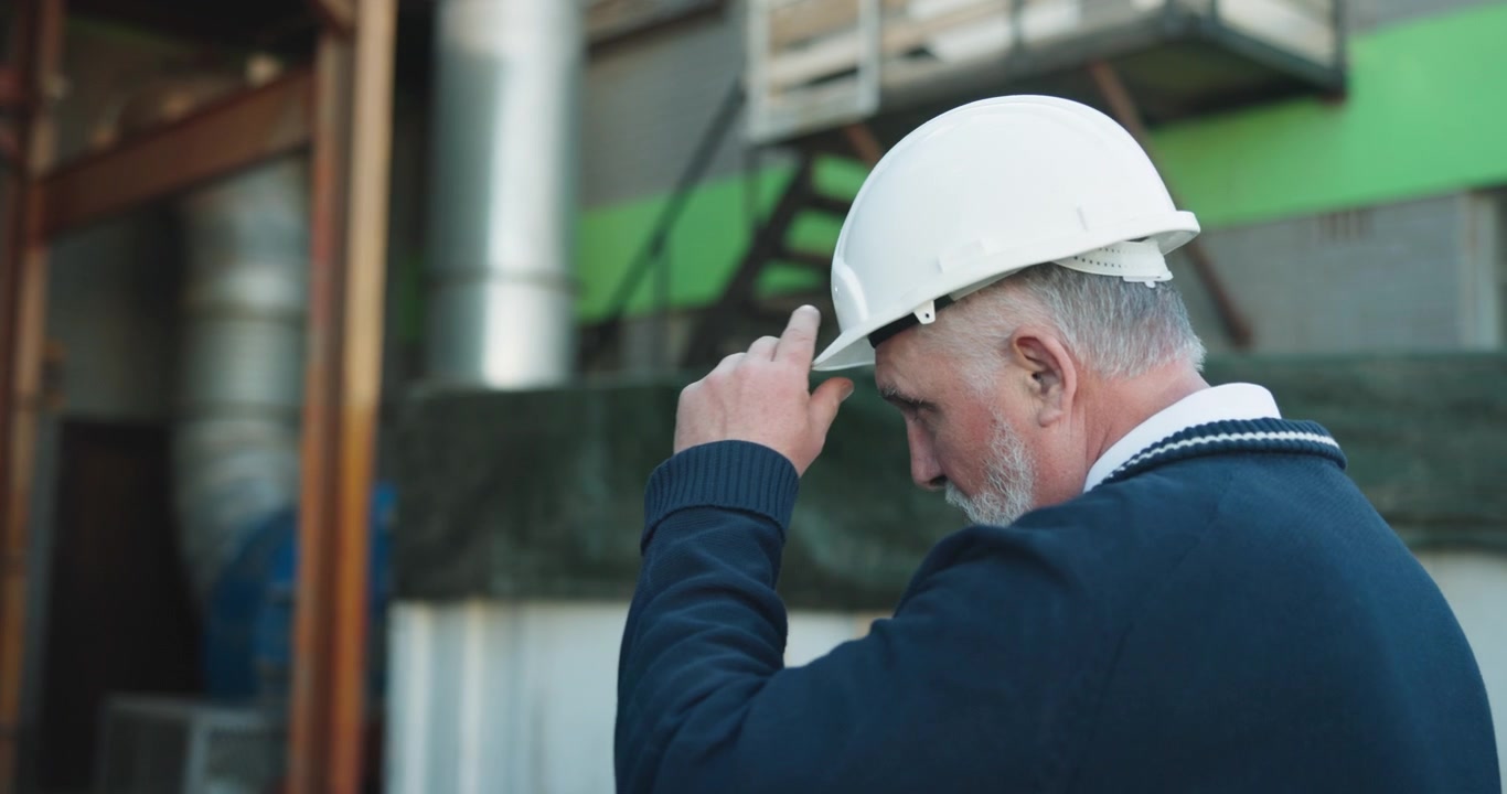 Senior Engineer Wearing Hard Hat Inspecting Industrial Facility