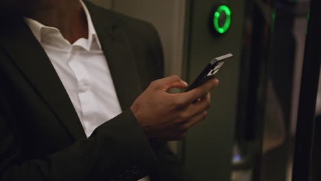 close up of businessman wearing suit commuting to work sitting in london underground tube train using mobile phone shot in real time