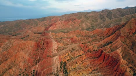 un dron volando sobre montañas rojas con diferentes tonos de rojo, capturando los picos escarpados y la belleza natural del paisaje