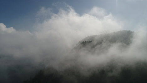 Drone-shot-of-slow-moving-fog-rolling-over-a-mountain-top