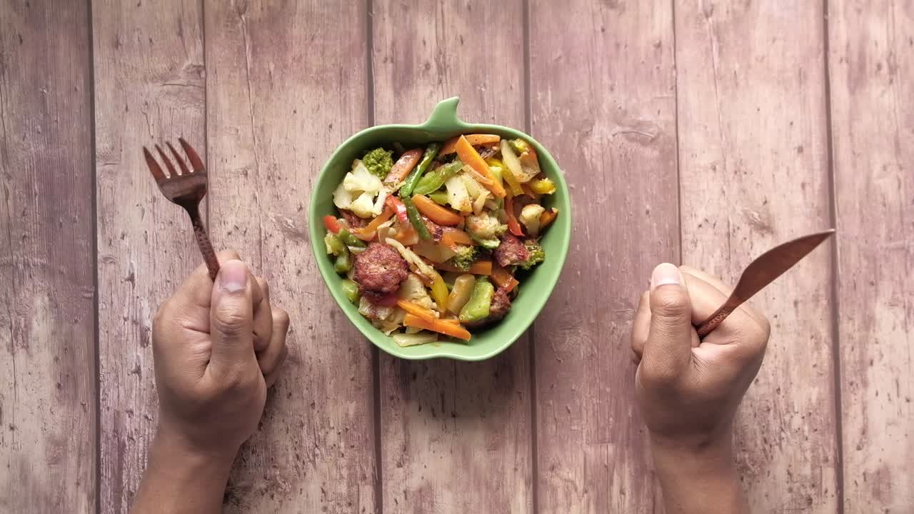 Joven con tenedor esperando desde en un plato lleno de verduras