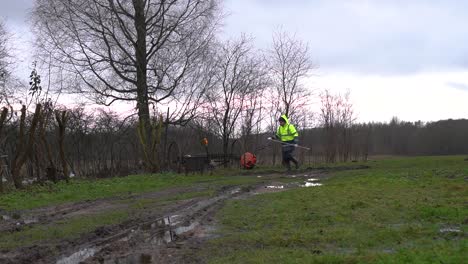 man in yellow reflective safety jacket use rake to repair damaged dirt road