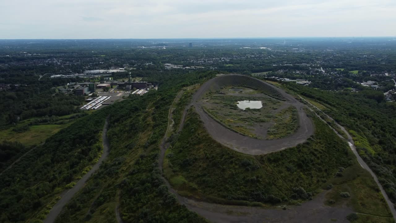 Slag heap with lake and industry in background