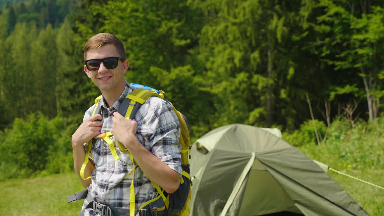retrato de un joven turista con una mochila mira la cámara muestra el pulgar en el gesto de