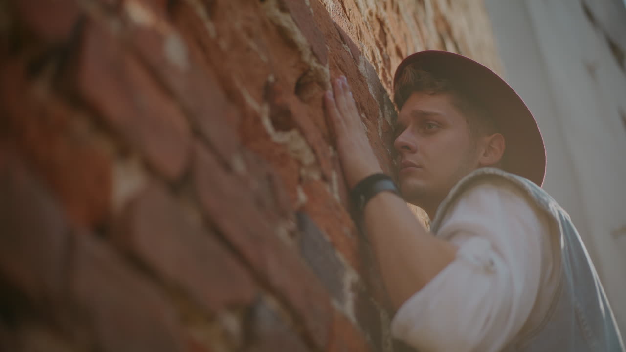 벽돌 벽 에 기대어 있는 남자