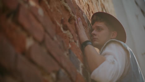 man leaning against a brick wall