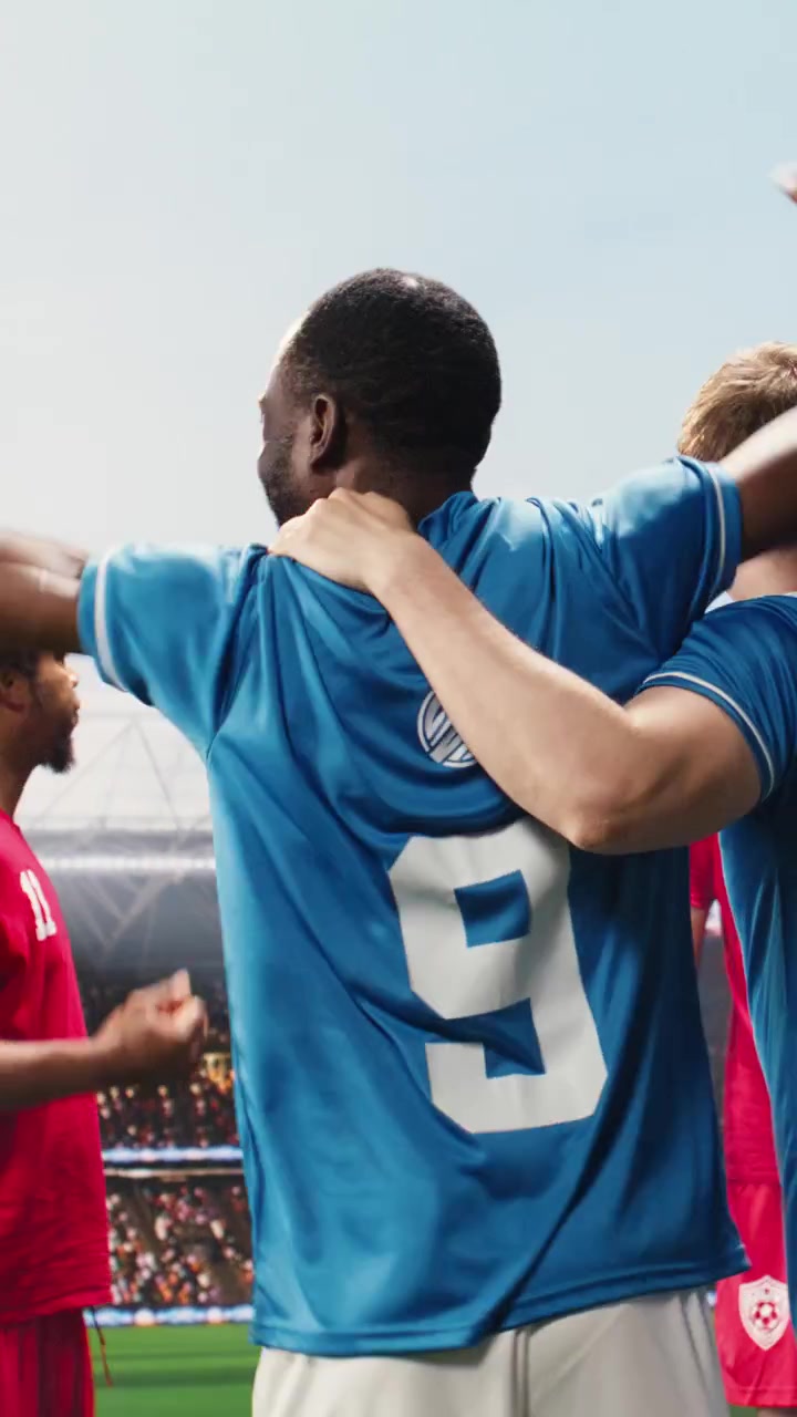 Video vertical. Futbolistas del equipo rojo celebrando la victoria del partido con los puños apretados y saltando.