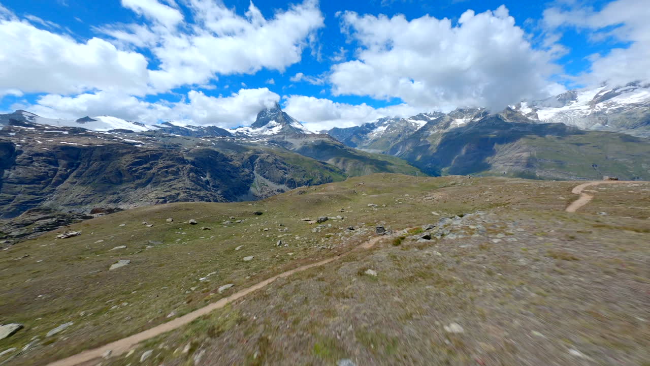drone volando bajo sobre los pastizales alpinos en zermatt, suiza, majestuosa cumbre de matterhorn vista en la distancia - fpv drone shot