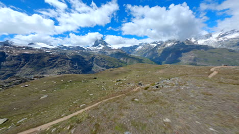 Drone-Volando-Bajo-Sobre-Los-Pastizales-Alpinos-En-Zermatt,-Suiza,-Majestuosa-Cumbre-De-Matterhorn-Vista-En-La-Distancia---Fpv-Drone-Shot