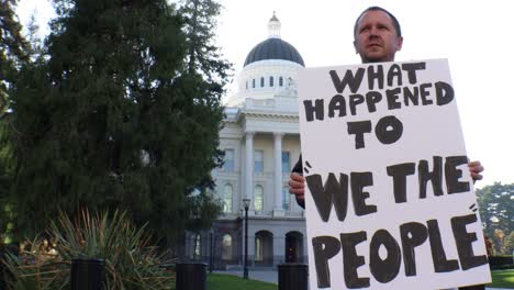 male political protester with what happened to we the people sign